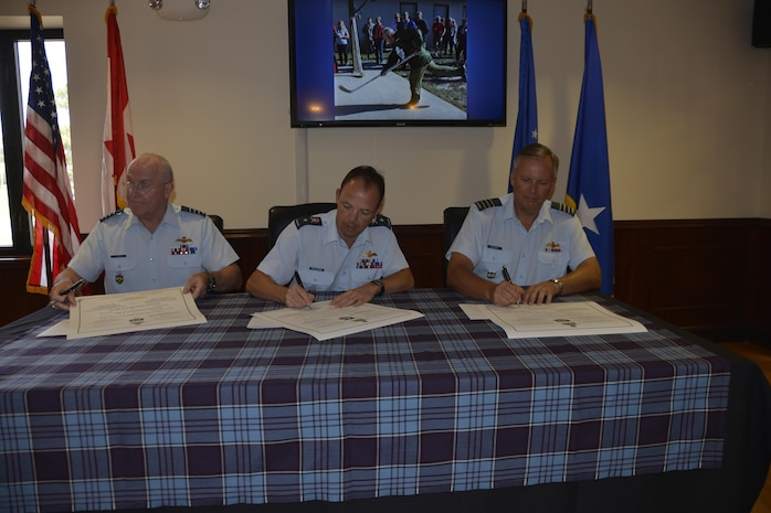 (From left) Royal Canadian Air Force LCol Larry Weir, outgoing Canadian Detachment Commander, RCAF BGen Alain Pelletier, Continental U.S. Aerospace Defense Region deputy commander and incoming Canadian Detachment Commander, RCAF LCol Brian Murray, complete the documents officially recognizing the change of command for the Canadian Detachment here May 18. (Air Force Photo released/Mary McHale)