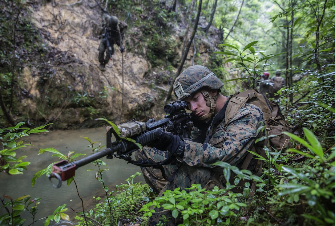 U.S. Marine Lance Cpl. Justin D. Enger sets up a security perimeter while the rest of his platoon rappels down the mountain at the Jungle Warefare Training Center, May 19, 2016 at Camp Gonsalves, Okinawa, Japan. Enger is a combat engineer with 9th Engineer Support Battalion, 3rd Marine Logistics Group, III Marine Expeditionary Force. Enger and his platoon attended the 5-day Course at JWTC. The course gives Marines the skills to shoot, move and communicate within a jungle environment. 
