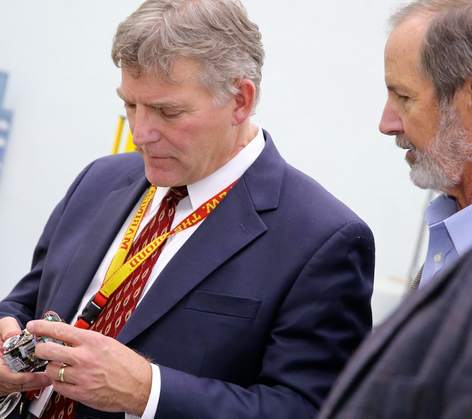 China Lake, Calif. - Executive Director Scott O' Neil, right, hands a component to Dr. John Burrow to take a closer look at the intricate parts that are assembled and manufactured in-house at Naval Air Warfare Center Weapons Division China Lake. "Additive manufacturing will fundamentally change how we think, how we do business, the cost variable, and how we make decisions," Burrow - Deputy Assistant Secretary of the Navy for Research, Development, Test and Evaluation - told 3D Printing exhibitors and visitors at the Navy Additive Manufacturing Showcase April 20, 2016. "I think you are about to see its operational and technical potential literally explode off the map." Burrow sponsored the event to explore innovative applications of additive manufacturing that benefit the warfighter and to highlight its impact throughout program lifecycles from early concepts, into component and system testing, and sustainment. 