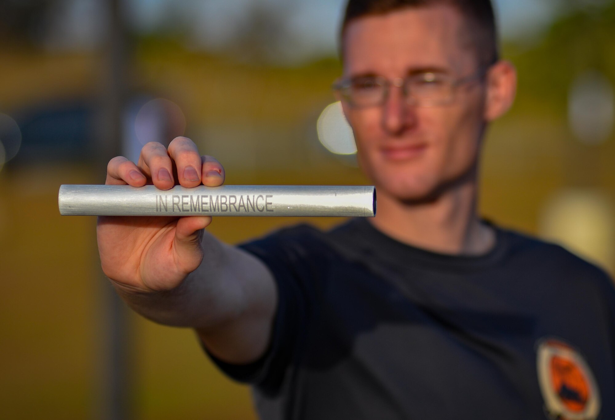 Staff Sgt. Collin Wanberg, munitions operations supervisor with the 36th Munitions Squadron, holds a rememberance baton during the Holocaust Memorial Walk May 26, 2016, at Andersen Air Force Base, Guam. The baton was ingraved with the inscription "Never Again - In Rememberance" to raise awareness of the stories of victims who suffered under the Nazi Regime in Germany 1933-1945. (U.S. Air Force photo by Staff Sgt. Alexander W. Riedel/Released)