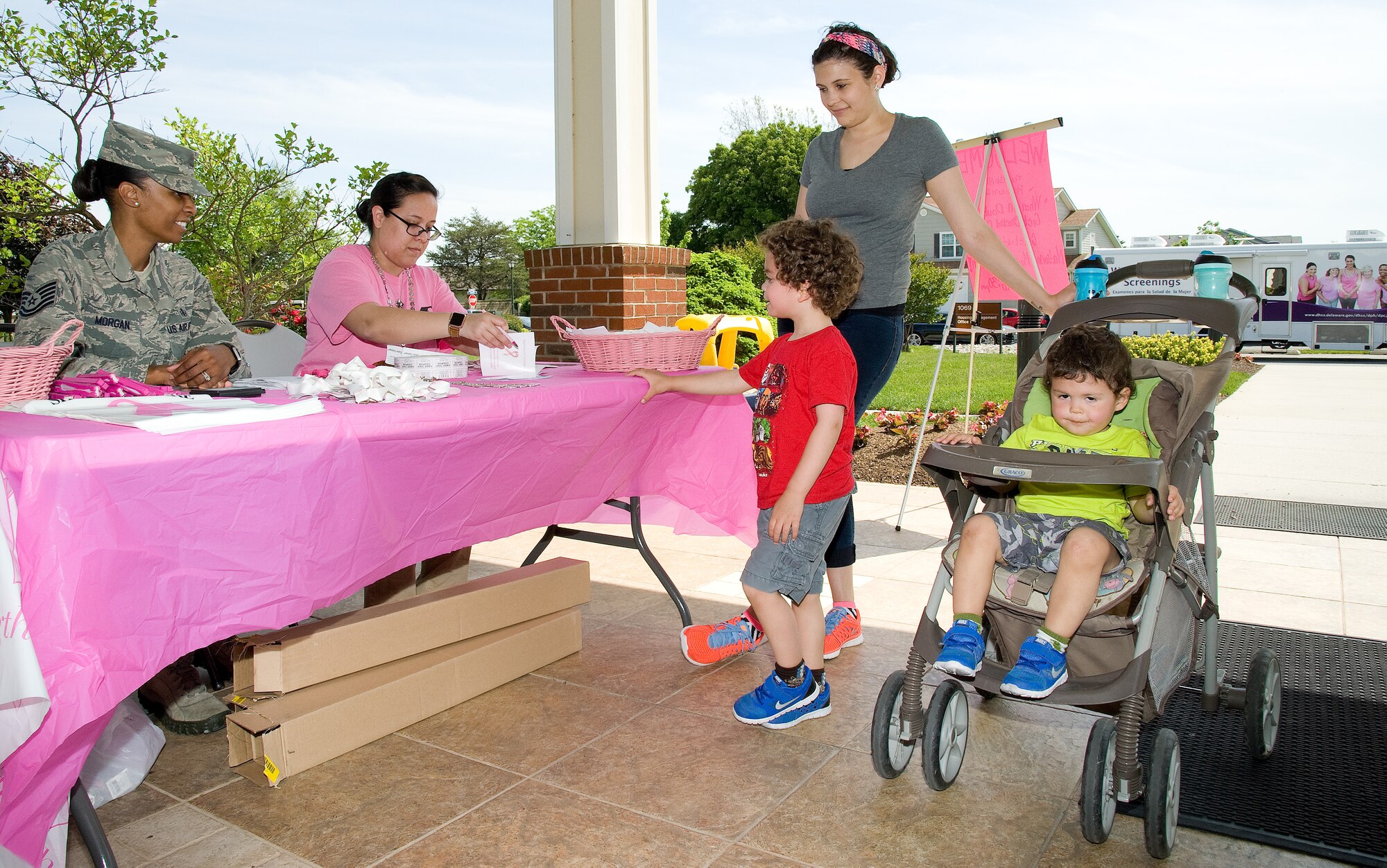 Staff Sgt. Crystal Andrews, 436th Medical Support Squadron unit training manager, prepares an event passport for Chernell Cruz, wife of Senior Airman Samuel Cruz, 436th Security Forces Squadron, and their sons Isaiah and Eli, as they prepare to enter the 'When in doubt, get checked out' event May 20, 2016, at the Housing Center on Dover Air Force Base, Del. Tech. Sgt. Lachaunda Morgan, 436th MDSS diagnostic imaging flight chief, left, waits to inform Cruz on door prizes she is eligible to win at the event presented by the 436th Medical Group in celebration of National Mammography Month. Patrons were offered free massages, Bod Pod and mammogram scheduling, information and food during the 4-hour event. (U.S. Air Force photo/Roland Balik)