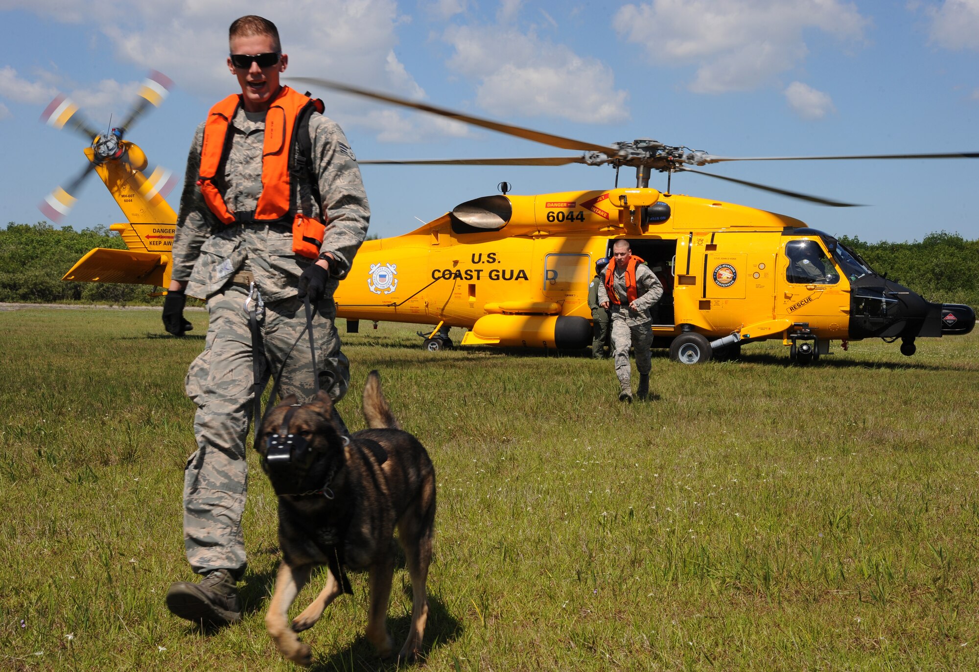 Senior Airman Austin Cook, military working dog (MWD) handler with the 6th Security Forces Squadron, and MWD Zeno exit an MH-60T Jayhawk during a training exercise at the U.S. Coast Guard Air Station in Clearwater, Fla., May 23, 2016. The purpose of the exercise is to condition the MWDs to helicopter noise and maneuvers before prior to deployment. (U.S. Air Force photo by Airman Adam R. Shanks)