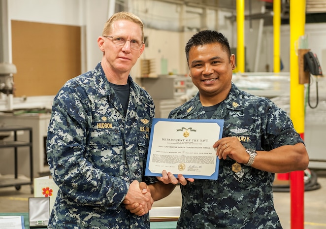 Captain Robert Hudson, Naval Nuclear Power Training Unit Charleston commander presents Chief Petty Officer Khalil Santos a Navy and Marine Corps commendation medal May 20, 2016, at Joint Base Charleston, S.C. Santos started the NPTU community service division in October 2015, leading more than 100 sailors who have volunteered nearly 10,000 hours in support of local nonprofit organizations. The program, created for Sailors on hold from NPTU, awaiting orders due to medical, legal or other reasons, provides the opportunity to give back to the local community while resolving personal matters. (U.S. Air Force photo/Staff Sgt. Jared Trimarchi) 