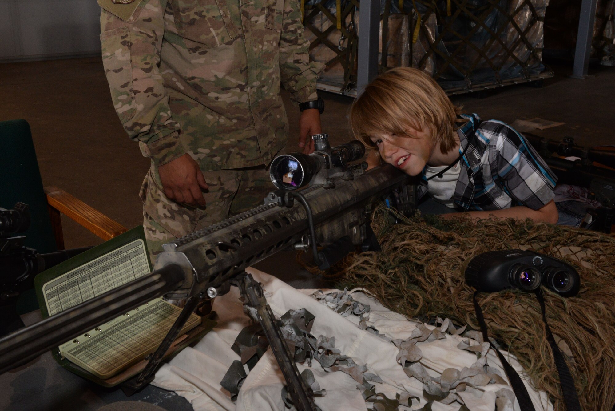 A dependent from Minot Air Force Base, N.D., looks through the scope of an M-107 sniper rifle during Operation Heroes May 21, 2016. Convoy response force Airmen from the 791st Missile Security Forces Squadron also brought M-4 assault rifles, an M-240B machine gun and an MK-19 grenade launcher, while Airmen from the 791st MSFS Tactical Response Force brought an M-24 sniper rifle. (U.S. Air Force photo/Airman 1st Class Jessica Weissman)