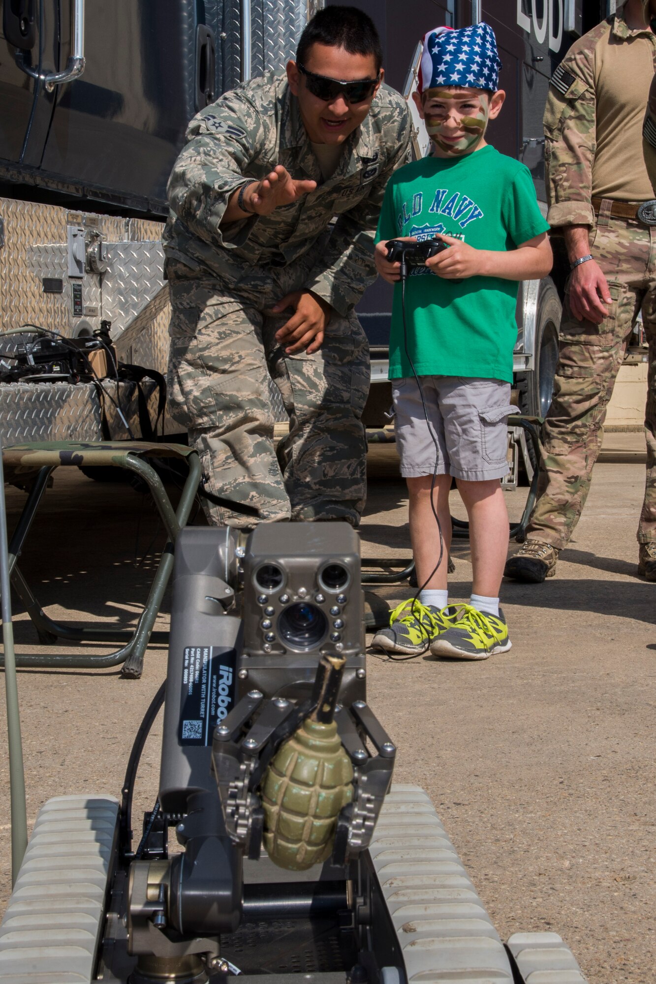 Airman 1st Class Ismael Del Toro, 5th Civil Engineer Squadron explosive ordinance disposal apprentice, helps a Minot Youth Center member remote control an EOD robot during operation heroes at Minot Air Force  Base, N.D., May 21, 2016. During operation heroes, kids got to experience many different jobs of the Air Force such as EOD, security forces, maintenance and others. (U.S. Air Force photo/Airman 1st Class Christian Sullivan)