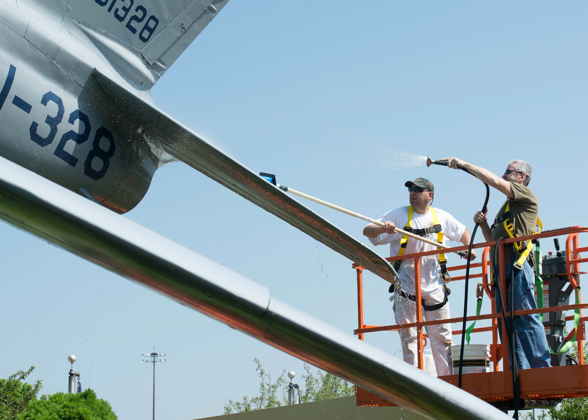 Peter C. Turilli, right, and Odilon C. Rodrigues, both painters assigned to the 66th Civil Engineering Division, wash the F-86 Sabre static display on base May 25. The cleaning, which is done annually, also included painting areas of the aircraft that were peeling. (U.S. Air Force photo by Jerry Saslav) 