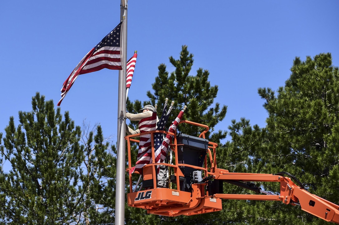 Air Force Staff Sgt. Steven Price attaches American flags to light poles on Stewart Avenue to commemorate Memorial Day at Peterson Air Force Base, Colo., May 23, 2016. Price is a structural journeyman assigned to the 21st Civil Engineer Squadron. He placed around 130 flags along the base’s main roads before the holiday weekend. Air Force photo by Staff Sgt. Amber Grimm