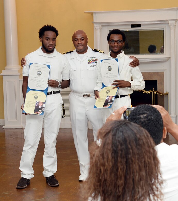 Lt. Cmdr. Donald Mitchell, senior nurse executive, Naval Branch Health Clinic-Albany, aboard Marine Corps Logistics Base Albany, presents Certificates of Appreciation to sons Jordon (left) and Davon (right) during his retirement celebration in Orange Park, Florida, May 14. Mitchell kicked-off his own retirement ceremony before the standing-room-only crowd of witnesses, donned in a sea of U.S. Navy summer uniforms and white civilian attire, who poured into the Orange Park Women’s Club to celebrate the honoree. The retiree devoted 30 years of active-duty service in the U.S. Navy.
