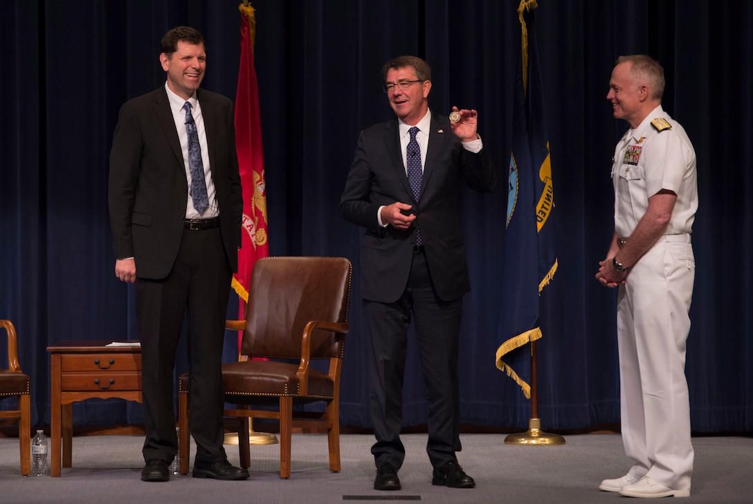 Defense Secretary Ash Carter holds up a challenge coin he received from Navy Rear Adm. P. Gardner Howe III, right, president of the U.S. Naval War College, after participating in a moderated discussion at the college while visiting the campus in Newport, R.I., May 25, 2016. DoD photo by Air Force Senior Master Sgt. Adrian Cadiz