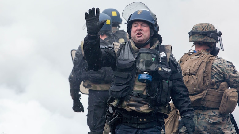A member of the French National Gendarmerie calls out orders through a cloud of CS gas during a bilateral riot-control exercise with U.S. Marines at the National Gendarmerie Training Center in St. Astier, France, May 13, 2016. This exercise helped reinforce the strong relationship between the Special Purpose Marine Air-Ground Task Force-Crisis Response-Africa and the French Gendarmes as the two units prepare to work together in possible real-world scenarios at embassies around Europe and Africa. 