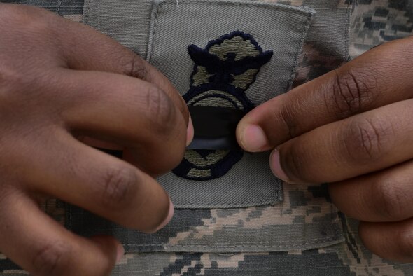 A 39th Security Forces Squadron defender, places a piece of black tape over their shield during a National Police Week retreat ceremony May 15, 2016, at Incirlik Air Base, Turkey. The black tape placed over the shield is a symbol of mourning fallen law enforcement officers. (U.S. Air Force photo by Staff Sgt. Caleb Pierce/Released) 