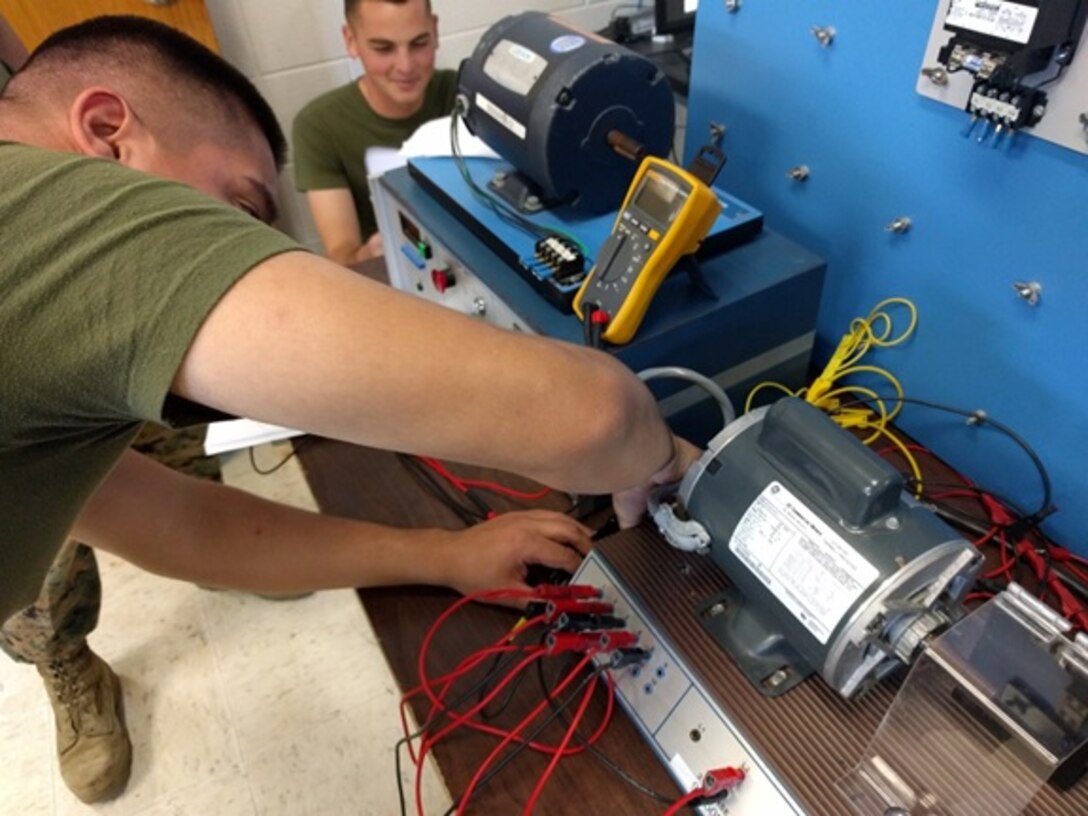 As part of a practical application Private First Class Wilfredo Gonzalez, a Marine from Chicago, IL attending Basic Refrigeration and Air Conditioning Technician course 3-16 (BRACT 3-16); wires a single phase capacitor start motor while following a wire diagram and schematic.
