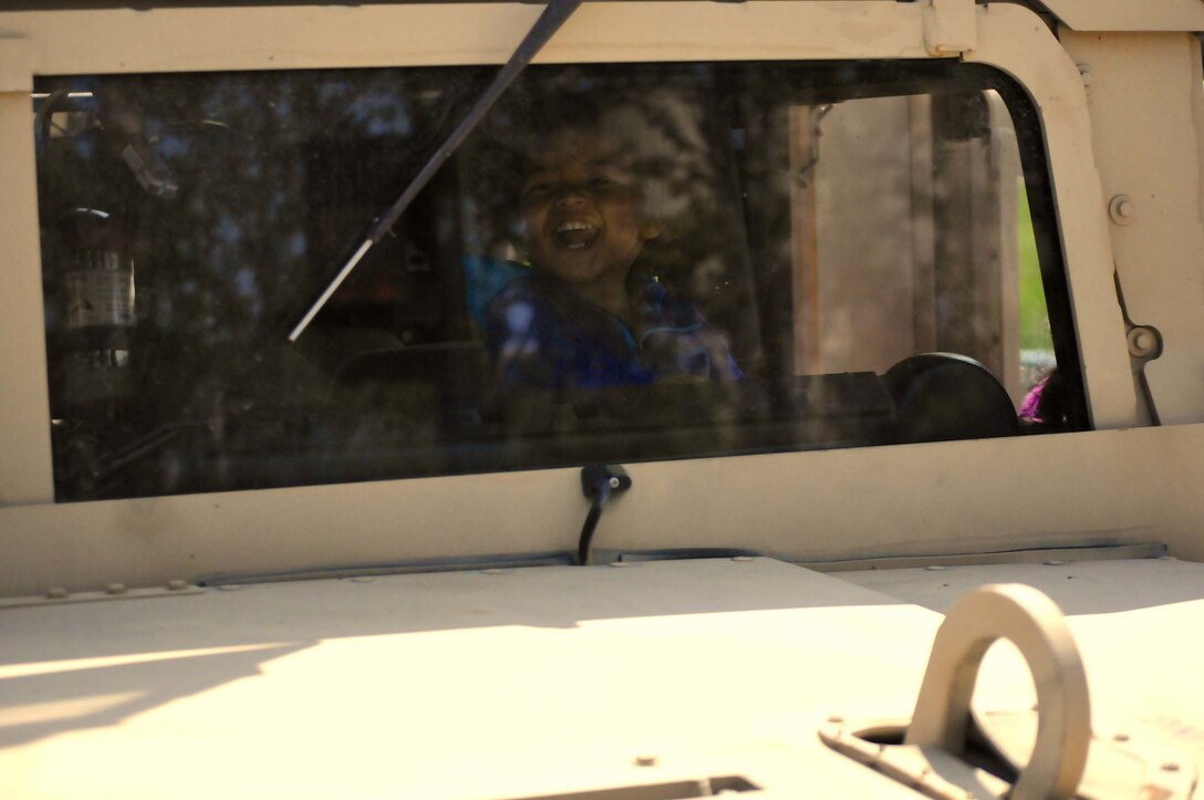 A child smiles while peering through the window of a High Mobility Multipurpose Wheeled Vehicle (HMMWV) during the Milwaukee Armed Forces Day event May 21.