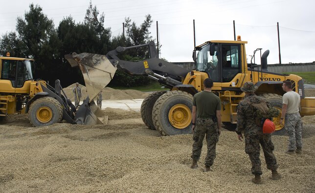 U.S. Marines fill a 50-foot crater during a two-day joint airfield damage repair exercise at Kadena Air Base, Japan, May 18, 2016. Airmen from the 18th Civil Engineer Squadron taught Marines and Navy Seabees how they repair damaged airfields. (U.S. Air Force photo/Senior Airman Omari Bernard/Released)