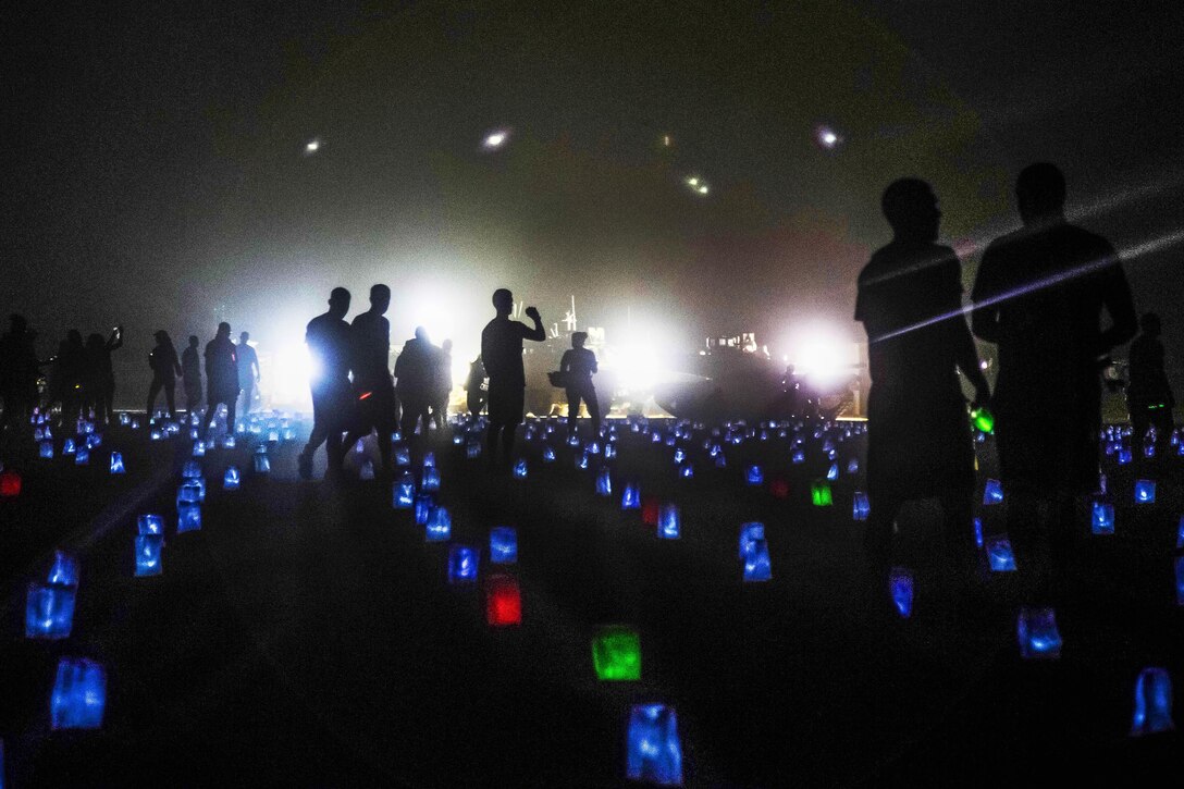Soldiers walk across a field of 6,800 memorial lights, which represent  U.S. service members who have fallen in Iraq and Afghanistan, during a Memorial Day vigil on Camp Buehring, Kuwait, May 26, 2014. Army photo by Sgt. Marcus Fichtl
