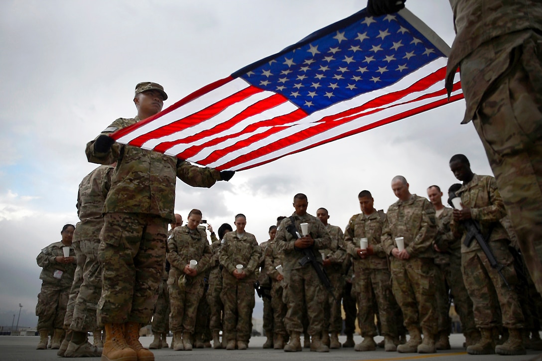 Air Force Senior Airman Jerick Encarnacion, left, holds a flag during a Memorial Day candle vigil march at Bagram Airfield, Afghanistan, May 26, 2014. Encarnacion is assigned to the 455th Expeditionary Logistics Readiness Squadron. Air Force photo by Staff Sgt. Evelyn Chavez