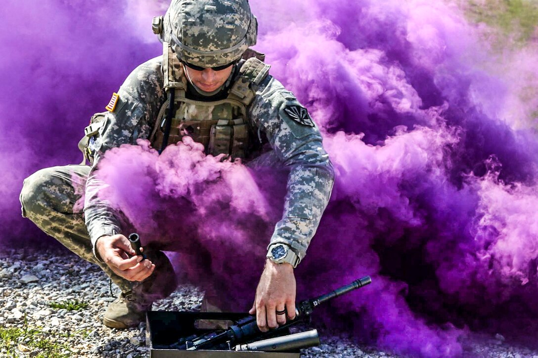 An Army flight medic assembles an M4 carbine as a thick cloud of smoke limits his visibility during the stress shoot portion of the Best Warrior Competition on Camp Bondsteel, Kosovo, May 21, 2016. Army photo by Staff Sgt. Thomas Duval