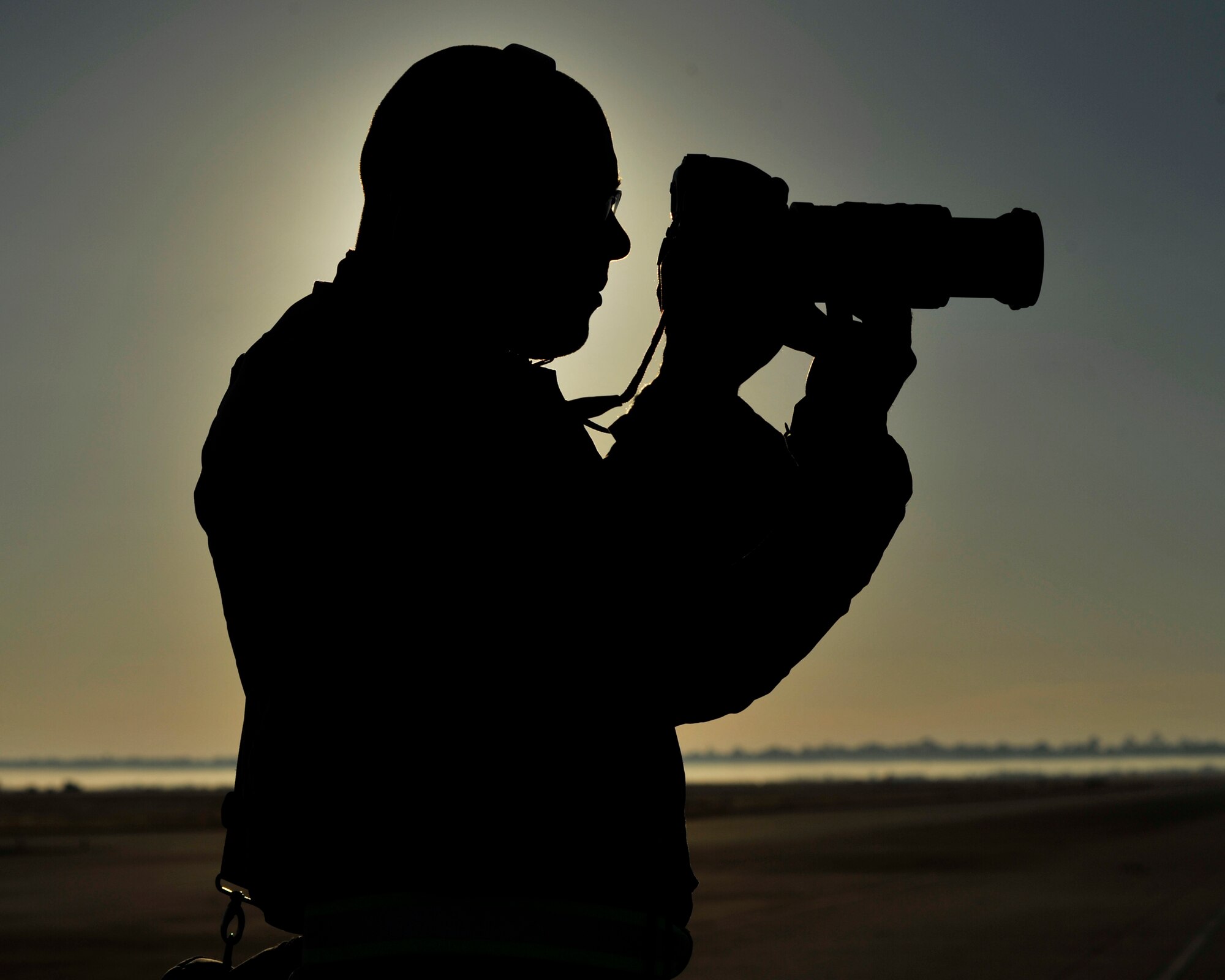 Senior Airman Solomon Cook, 325th Fighter Wing Public Affairs photojournalist, takes a photo on the flightline, Dec. 10, 2015, at Tyndall AFB. The Public Affairs Office provides photo documentation of all important events on the base including exercises, retirements and promotion ceremonies. (U.S. Air Force photo by Senior Airman Sergio Gamboa)  