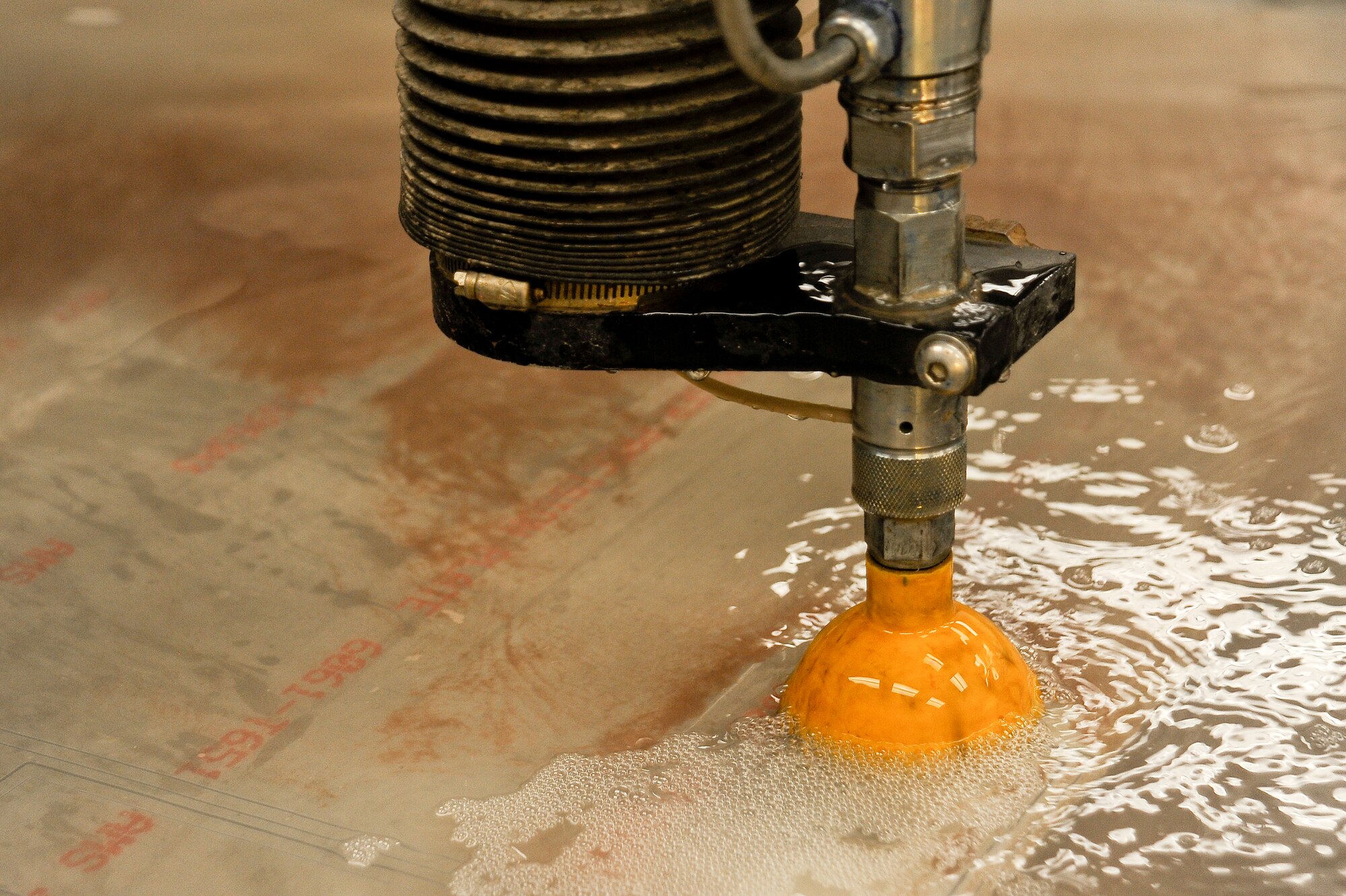 A water jet machine cuts out aluminum at MacDill Air Force Base, Fla., May 20, 2016. Metals technology Airmen program the machine to cut the metal and create small hangers for the rack. (U.S. Air Force photo by Airman 1st Class Mariette Adams)