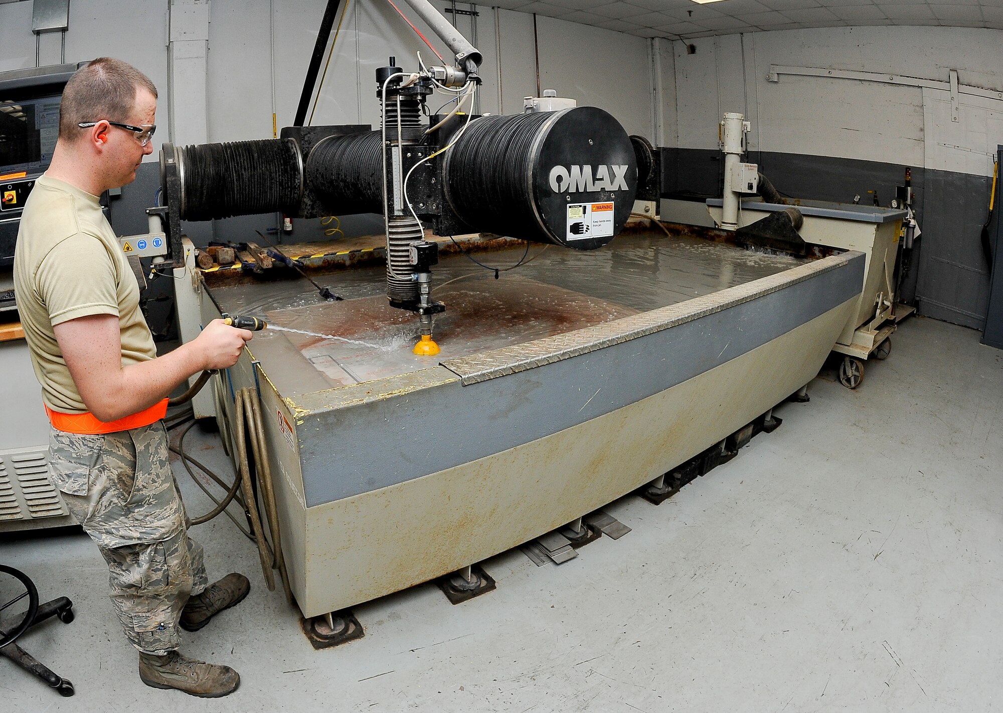 Senior Airman Brandon Gentry, an aircraft metals technology technician with the 6th Maintenance Squadron, rinses off metal in the water jet machine at MacDill Air Force Base, Fla., May 20, 2016. The metal must be rinsed off to ensure the water jet machine is properly cutting small hangers for the rack. (U.S. Air Force photo by Airman 1st Class Mariette Adams)