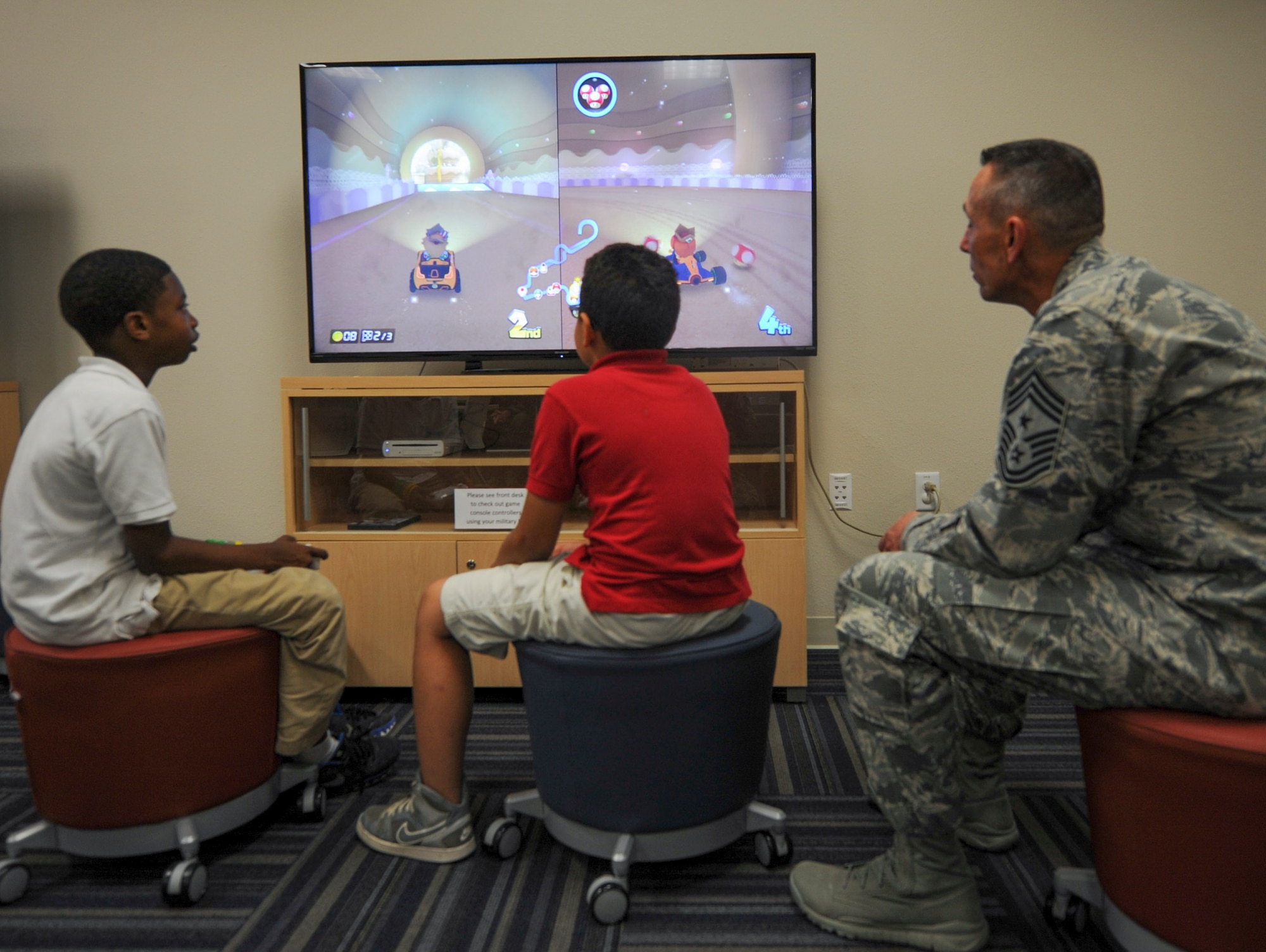 Right, U.S. Air Force Chief Master Sgt. Todd Petzel, 18th Air Force command chief, plays a video game with military children May 23, 2016, at the Walter’s Community Support Center on Little Rock Air Force Base, Ark. Petzel and U.S. Air Force Lt. Gen. Sam Cox, 18th Air Force commander, visited Airman support facilities as part of a comprehensive tour of Little Rock AFB. (U.S. Air Force photo by Senior Airman Harry Brexel)