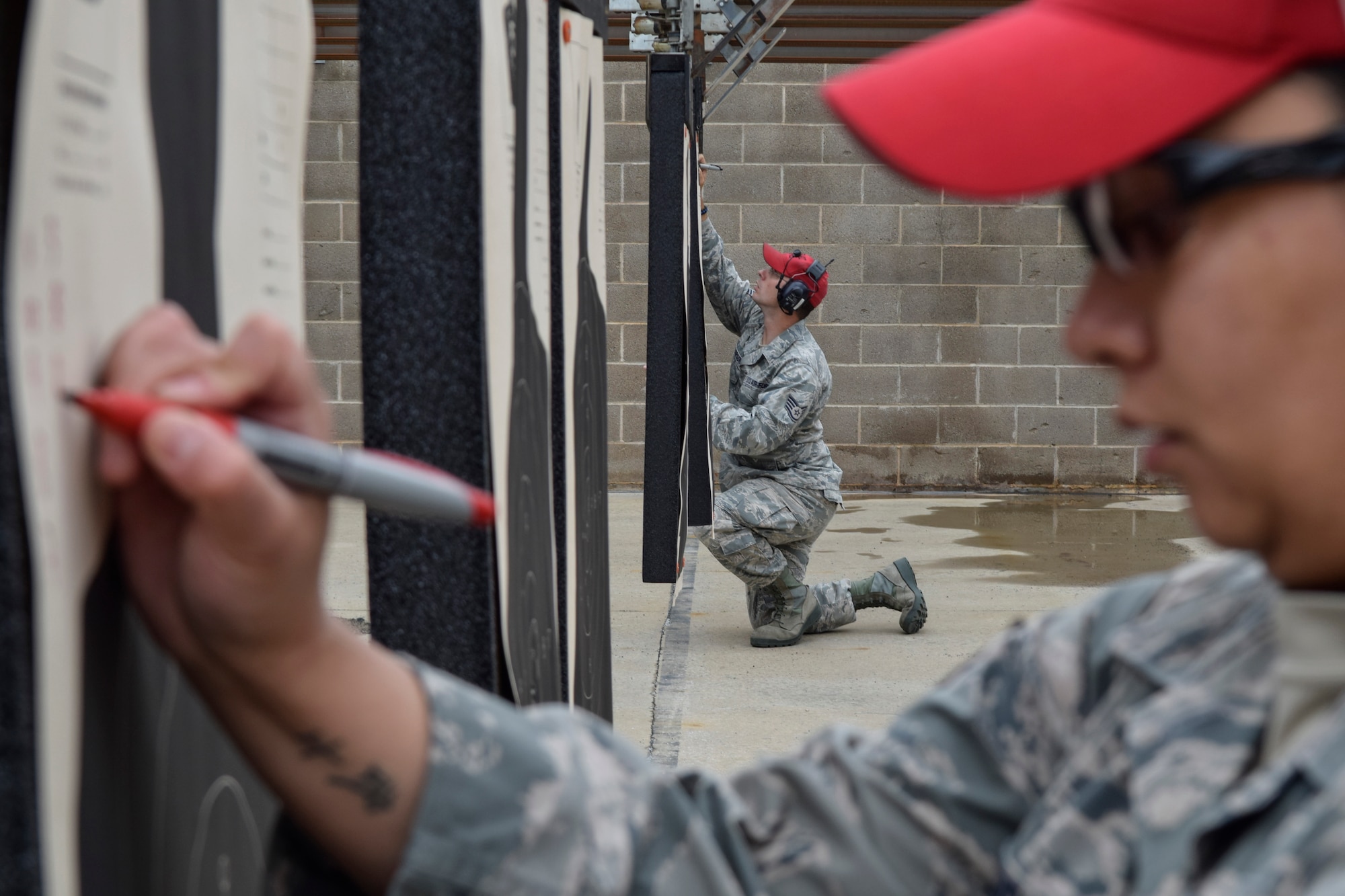 Staff Sgt. Greg Peterson is framed by Staff Sgt. Joanna Richmond as the two combat arms instructors from the 72nd Security Forces Squadron tally scores on targets during a shooting competition held by the squadron as part of Police Week 2016 activities on May 17. Teams of shooters from multiple units assigned to the base competed in the event which challenged shooters in both speed and accuracy drills. (Air Force photo by Greg Davis/Released)