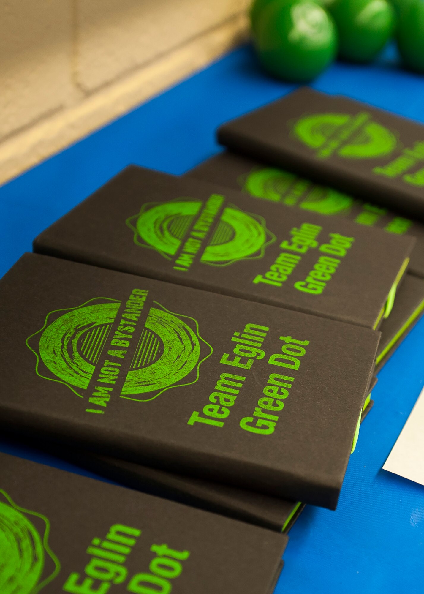 Notebooks displaying Green Dot’s training message, “I Am Not A Bystander” are stacked during base leadership training May 9 at Eglin Air Force Base, Fla. The Green Dot program will be used to train Airmen here and across the Air Force to help reduce power-based interpersonal violence. The idea behind GD is that the small proactive actions of intervention by bystanders will influence the behavior of others to create a ‘new normal’ within their social groups and communities impacting cultural change, teaching that violence and inaction are unacceptable. GD training began recently and is mandatory for all base personnel. (U.S. Air Force photo/Ilka Cole)  


