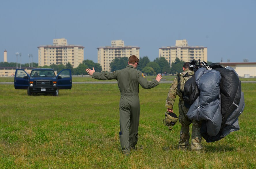 2nd Lt. Bobby Thomas Jr., 36th Airlift Squadron C-130 Hercules navigator, and Tech. Sgt. Benjamin Johnis, 374th Operations Support Squadron NCO in charge of Survival, Evasion, Resistance and Escape operations, leave the drop zone after Johnis’ successful landing at Yokota Air Base, Japan, May 23, 2016. Every day a variety of personnel, from drop zone coordinators to aircraft commanders to jump masters, communicate to keep Yokota’s air drop operations safe and successful. (U.S. Air Force photo by Airman 1st Class Elizabeth Baker/Released)