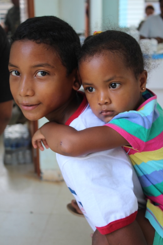 A young boy carries his sister while his mother receives basic health care services during a Joint Task Force-Bravo-led Medical Readiness Training Exercise in Alamikamba, Nicaragua, May 18, 2016. Many of the children in the Miskito Coast of Nicaragua suffer from malnutrition and lack vitamins. During the MEDRETE, preventive medication was provided to both adults and children as part of a care bag they received prior to a medical consultation. (U.S. Army photo by Maria Pinel)   