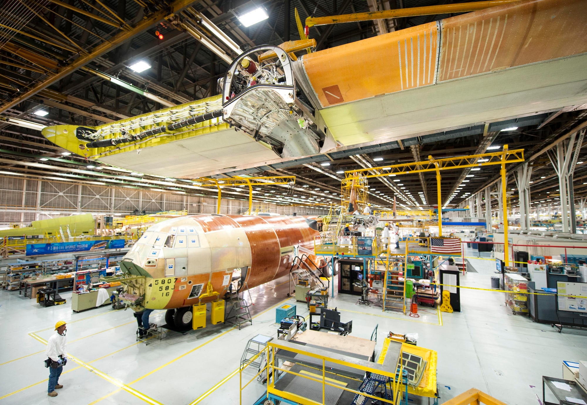 A wing is lifted above a C-130J at the Lockheed Martin Aeronautics facility in Marietta, Georgia, before being attached to the aircraft. The 374th Airlift Wing at Yokota Air Base, Japan, is scheduled to receive its first C-130J (the aircraft in the photo) by the end of 4th quarter 2016. (Photo by Andrew McMurtrie)