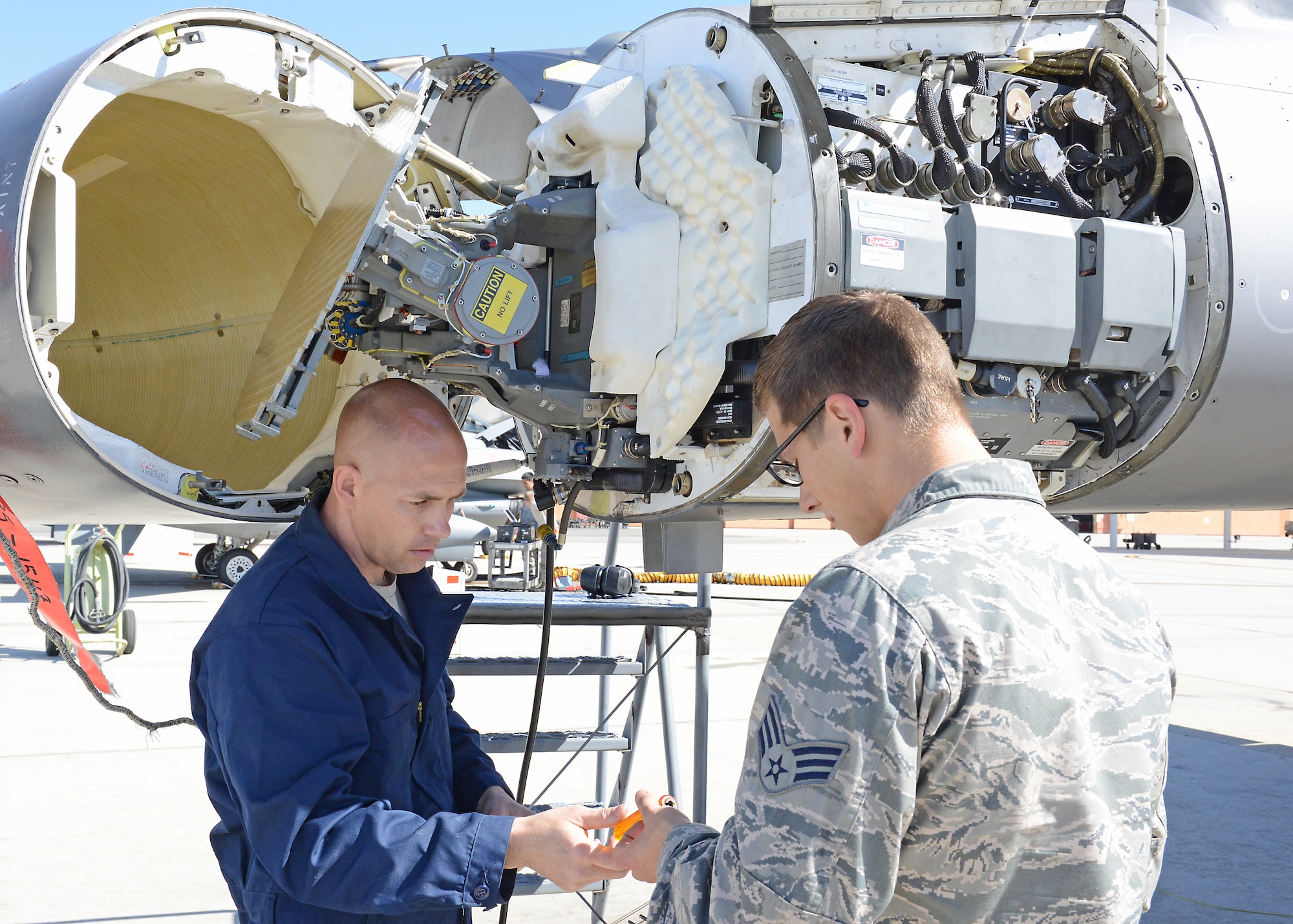 Senior Master Sgt. Samuel Rock, an Air Force Reserve volunteer from Seymor Johnson Air Force Base, South Carolina, works with Senior Airman Quilan Johansen of the 412th Aircraft Maintenance Squadron on an F-16 radar waveguide pressurization. the Air Force Reserves are here to augment Edwards F-16 support for KC-46 Pegasus testing. (U.S. Air force Photo by Kenji Thuloweit.)