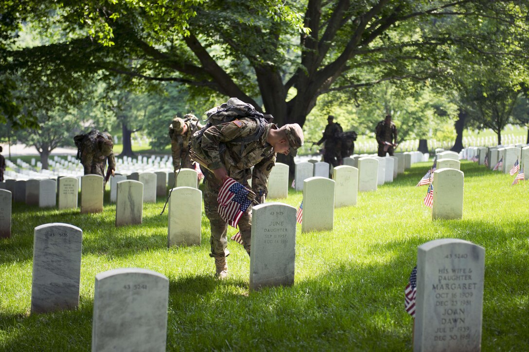Soldiers place American flags in front of headstones during "Flags In" at Arlington National Cemetery in Arlington, Va., May 26, 2016. Army photo by Rachel Larue