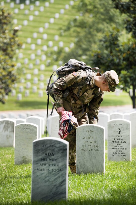 Army Pfc. Jonathan Gretz places an American flag in front of a headstone during "Flags In" at Arlington National Cemetery in Arlington, Va., May 26, 2016. Gretz is assigned to the 3rd U.S. Infantry Regiment, known as "The Old Guard." Army photo by Rachel Larue