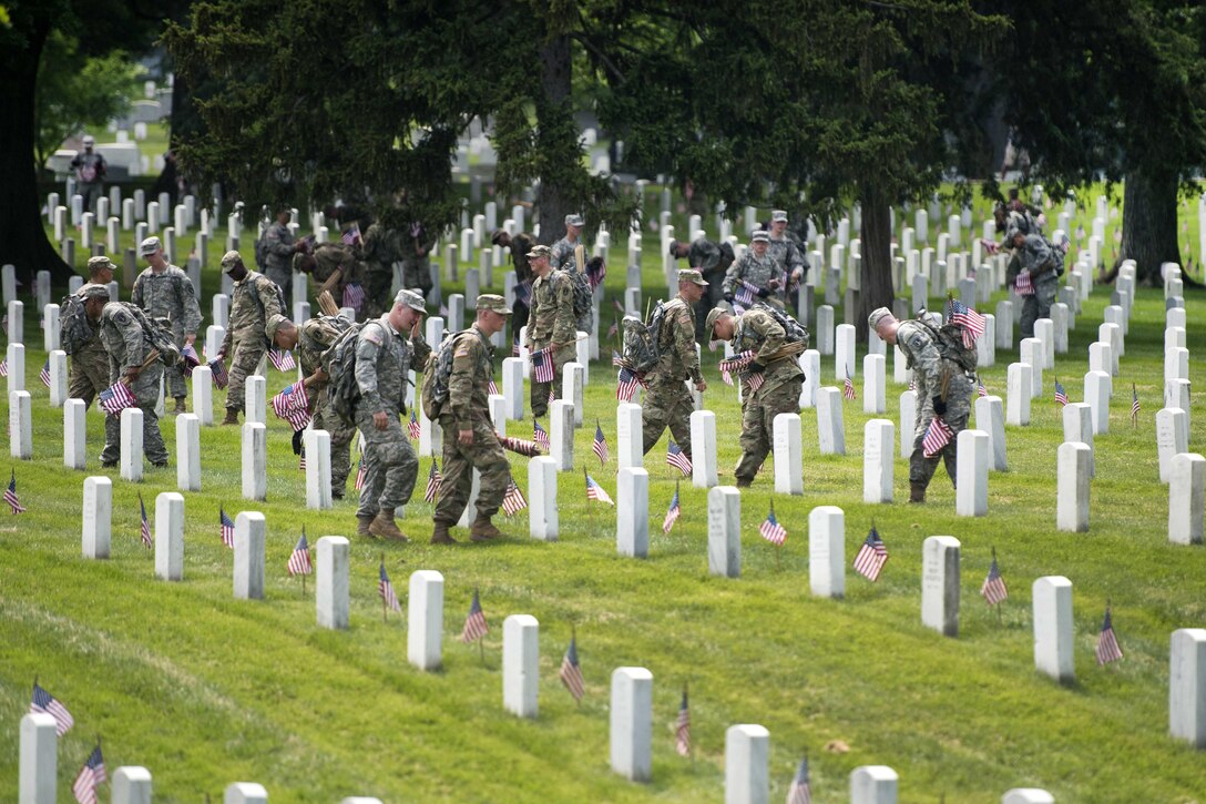 Members of the 3rd U.S. Infantry Regiment, known as "The Old Guard," place American flags in front of headstones during "Flags In" at Arlington National Cemetery in Arlington, Va., May 26, 2016, Army photo by Rachel Larue