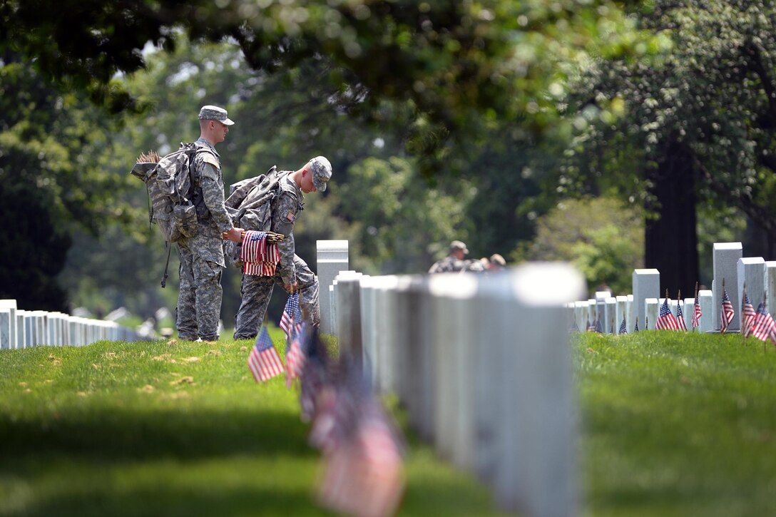 Soldiers place American flags in front of headstones during "Flags In" at Arlington National Cemetery in Arlington, Va., May 26, 2016. DoD photo by Marvin D. Lynchard