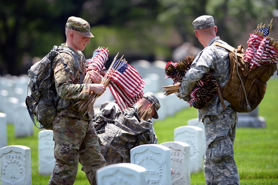 Soldiers place American flags in front of headstones during "Flags In" at Arlington National Cemetery in Arlington, Va., May 26, 2016. DoD photo by Marvin D. Lynchard