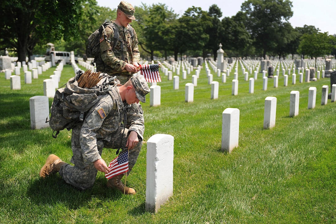 Soldiers pay their respects after placing a small American flag in front of a headstone during "Flags In," an annual event before Memorial Day honoring our nation’s fallen service members at Arlington National Cemetery in Arlington, Va., May 26, 2016. DoD photo by Marvin D. Lynchard