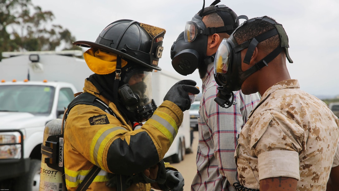 A firefighter with the Marine Corps Air Station Miramar Fire Department decontaminates a suspect and a military police officer with the Provost Marshal’s Office during a Chemical, Biological, Radiological, Nuclear and High-Yield Explosives exercise at the gas chamber aboard Marine Corps Air Station Miramar, Calif., May 18, 2016. The exercise revolved around PMO, the Miramar Fire Department, Explosive Ordnance Disposal, and Aircraft Rescue and Firefighting working together to identify and eliminate the threat of a simulated clandestine drug lab.