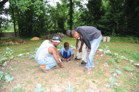 Staff Sgt. Montaski McCoy shows neighborhood children in West Montgomery seedlings taking root where they had planted them at a community garden. He started it to help get them interested in alternatives to the smoking, drugs, and violence that is prevalent in the area. Once McCoy started building the garden, neighbors pitched in to help. He has seen able to educate them on how plants and vegetables are grown and the work involved in bringing them from the garden to the table. (U.S. Air Force photo by Lt. Col. Jerry Lobb)