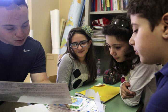 RPSA Alexander Varner, a religious program specialist with Special Purpose Marine-Air Ground Task Force Crisis Response-Africa, reads a book to children at 3rd Circolo Didattico ‘’Giovanni Paolo II’’ Gravina Di Catania, Italy, May 18, 2016.  The Marines and sailors interacted with the children, going over some English for an upcoming test, as well as creating and participating in games during the children’s recess period. (U.S. Marine Corps photo by Cpl. Alexander Mitchell/released)