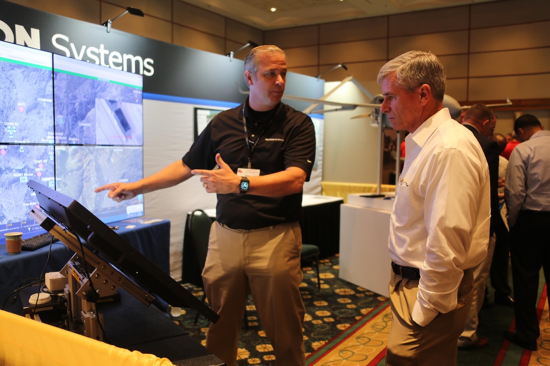 Ken Phillips,left, showcases an exhibit during the 45th Annual Marine Corps Aviation Association Symposium and Marine Aviation Summit at New Bern, N.C., May 17, 2016. Hundreds of naval aviators gathered at the convention center for the opening brief to the weeklong event. Senior leaders gathered to discuss the future of Marine Corps aviation and the steps the Corps is taking to reach its set goals. Phillips is a manager with Textron Systems. (U.S. Marine Corps photo by Cpl. N.W. Huertas/Released)