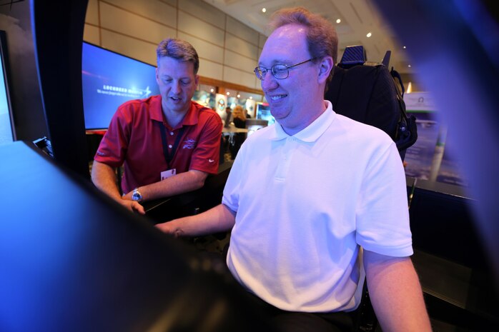 Mark Bosley, left, explains the controls of the Lockheed Martin  F-35 simulator to an attendee during the 45th Annual Marine Corps Aviation Association Symposium and Marine Aviation Summit at New Bern, N.C., May 17, 2016. Hundreds of naval aviators gathered at the convention center for the opening brief to the weeklong event. Senior leaders gathered to discuss the future of Marine Corps aviation and the steps the Corps is taking to reach its set goals. Bosley is a Lockheed Martin F-35 demonstrator instructor pilot. (U.S. Marine Corps photo by Cpl. N.W. Huertas/Released)