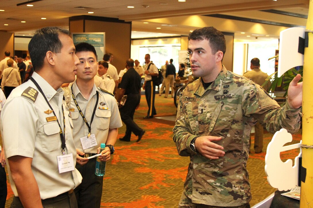 Army 1st Lt. Christopher J. Collins, a platoon leader assigned to the 25th Infantry Division’s Lightning Academy, discusses the academy’s functions with officers from Singapore during the fourth annual Land Forces Pacific Symposium and Exhibition in Honolulu, May 25, 2016. Army photo by Staff Sgt. Brandon C. McIntosh
