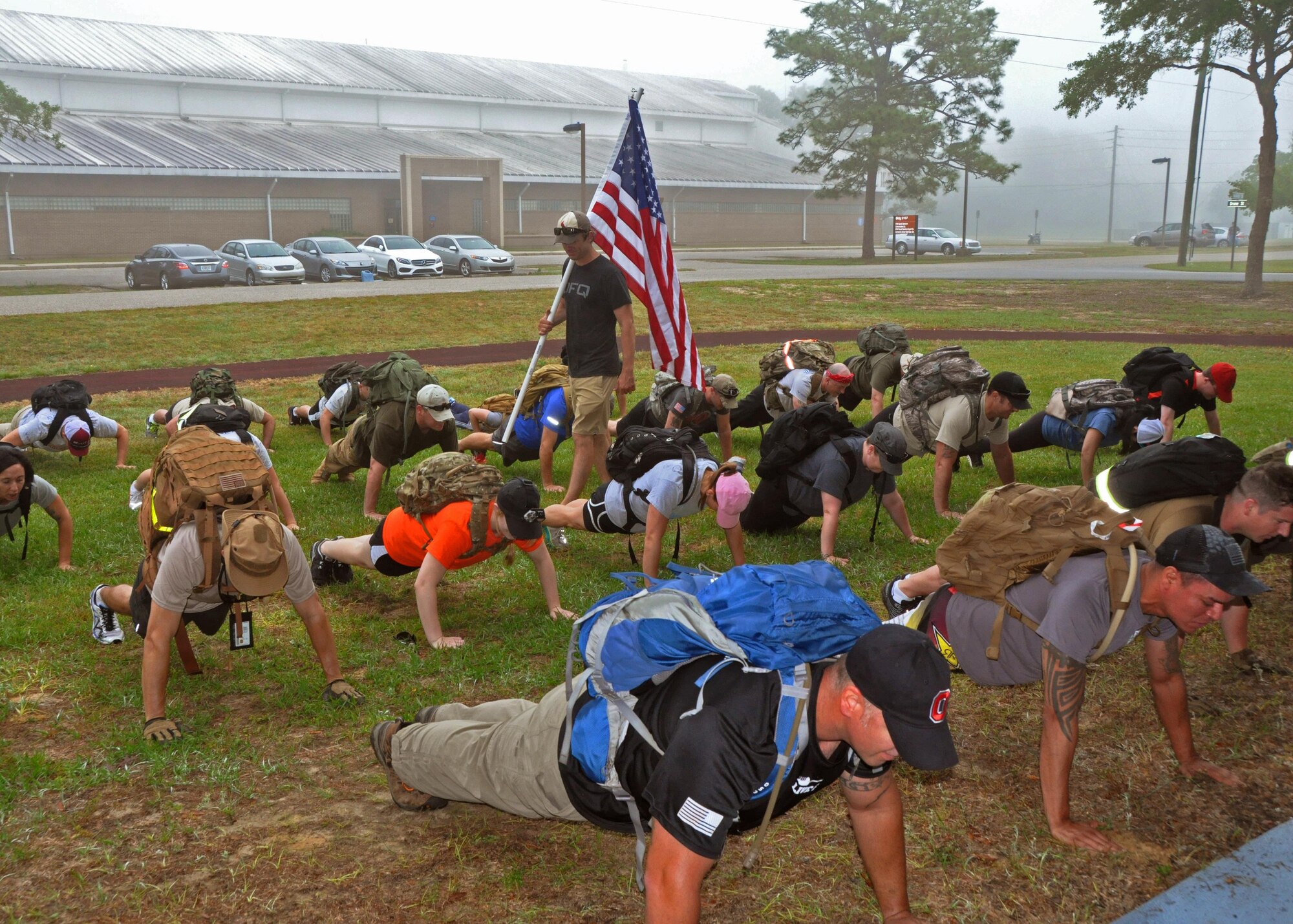 Cadre leader Brad Rucker, a former special operations member, carries the flag while barking orders to 919th Special Operations Wing Airmen during the warmup phase of a GoRuck Challenge event May 12, 2016 at Duke Field, Fla.   The teambuilding exercise, based on special operations fitness training, put participants through a five-hour series of physically and mentally exhausting scenarios along an eight-mile ruck march.  (U.S. Air Force photo/Dan Neely)