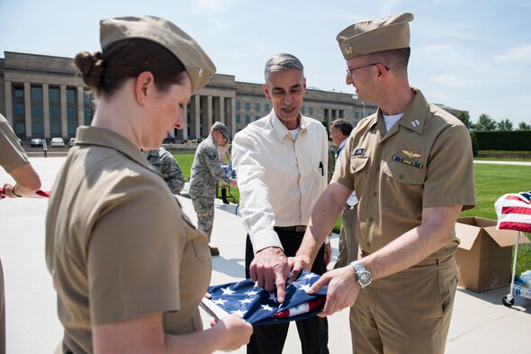 Navy Lt. Christopher Lawson gets instructions from Army veteran Alvin Nieder on how to properly fold a flag during a flag-raising event that Nieder has organized in honor of Memorial Day outside of the Pentagon in Washington, D.C., May 25, 2016. (U.S. Air Force photo/Staff Sgt. Alyssa Gibson)
