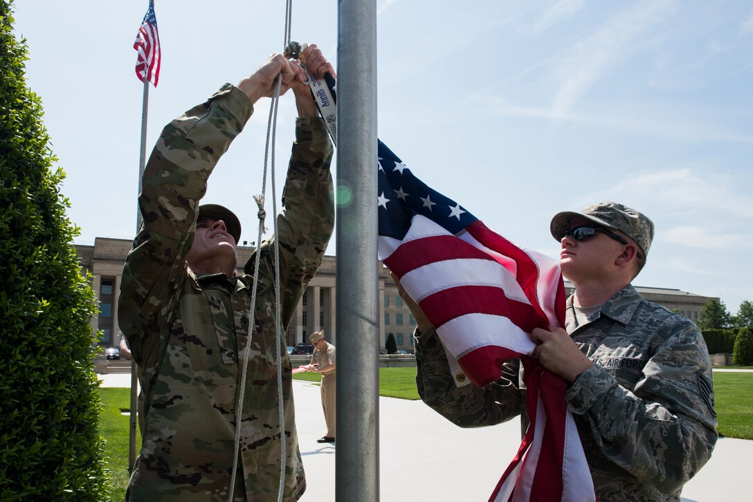 Army Sgt. Maj. Tim Wagley, left, and Air Force Staff Sgt. Bryan Payton raise a flag in honor of Memorial Day outside of the Pentagon in Washington, D.C., May 25, 2016. (U.S. Air Force photo/Staff Sgt. Alyssa Gibson)