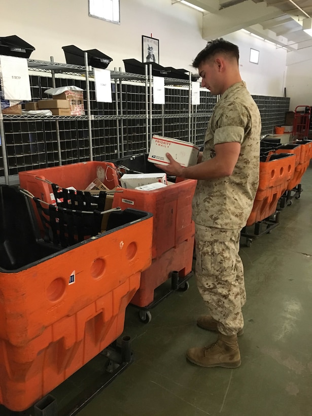 LCpl Cullen T. Holt sorts packages in the MCCES mailroom before Marines come to pick up mail.