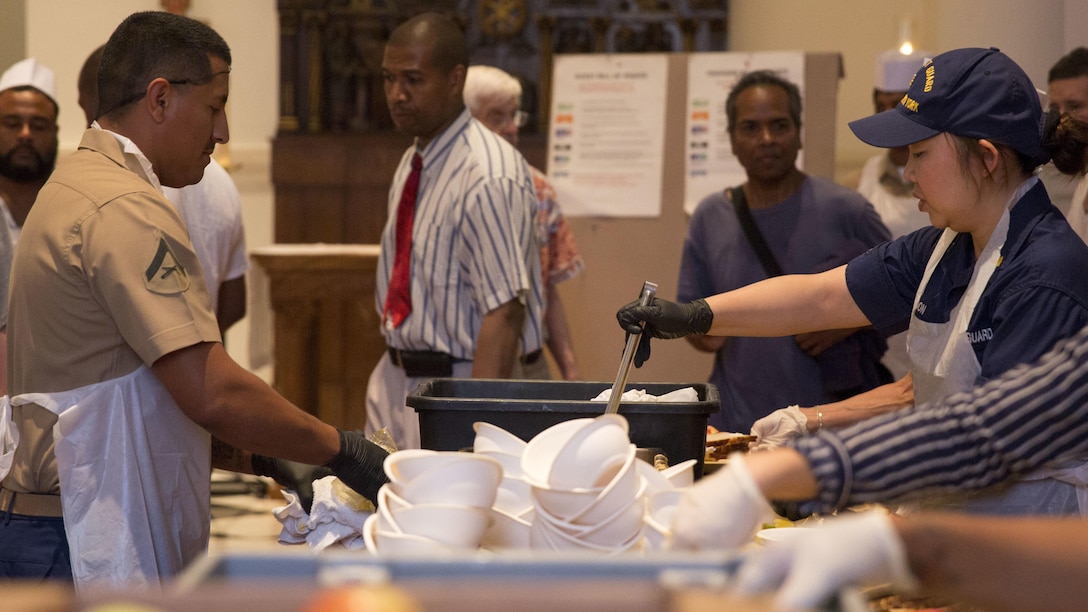 U.S. Marine Corps Lance Cpl. Alejandro Olivarez, left, motor transportation operator with Headquarters and Support Company, 3rd Battalion, 6th Marine Regiment, and U.S. Coast Guard Lt. Cmdr. Mimi Moon, port state control chief with Sector New York, serve food at the Holy Apostles Soup Kitchen in New York, May 27, 2016 during Fleet Week. U.S. Marines, sailors and coast guardsmen visited the city to interact with the public, demonstrate capabilities and teach the people of New York about America's sea services.
