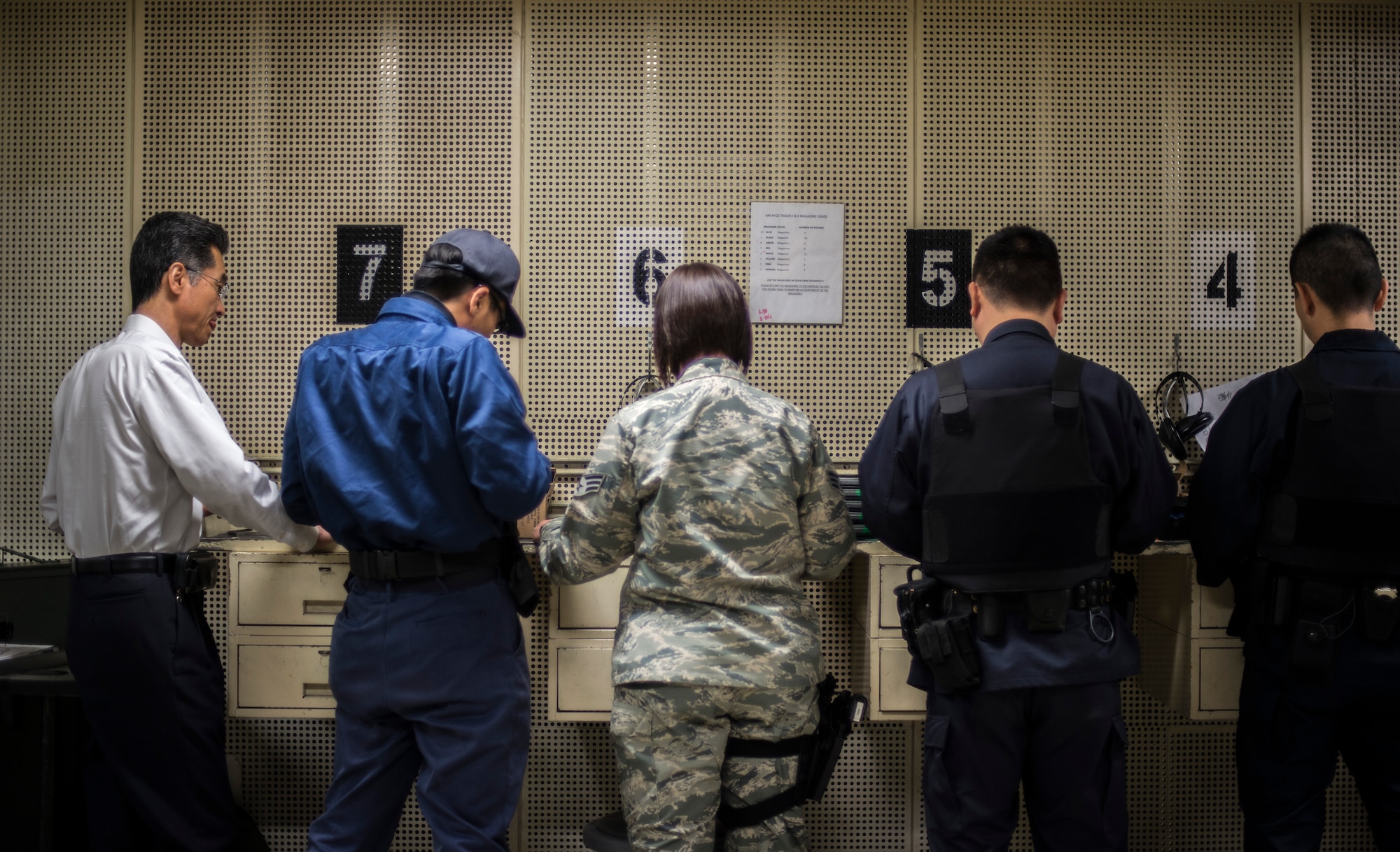 U.S. Air Force Senior Airman Lauren Moschell, a range safety official and acting NCO in charge of physical security with the 35th Security Forces Squadron, teaches Japanese National Civilian Guard members how to load ammunition into magazines more efficiently at Misawa Air Base, Japan, May 25, 2016. Mr. Mitsugu Sakaoka (far left), a civilian guard supervisor with the 35th SFS, is a translator who assists the instructor during the course, making sure the correct commands and safety procedures are communicated correctly. (U.S. Air Force photo by Senior Airman Brittany A. Chase)