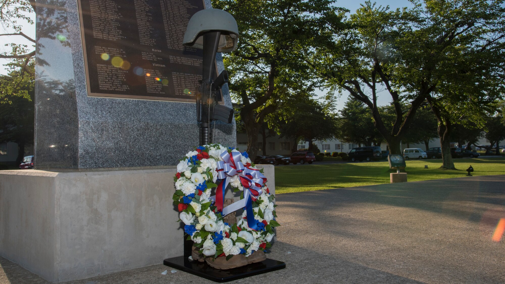 A battlefield cross adorned with a wreath of flowers rests on the edge of a Medal of Honor Recipients plaque at Misawa Air Base, Japan, May 27, 2016. A battlefield cross is formed when dog tags are hung from the neck of a rifle, which is then based in military boots and topped with a hard-shelled helmet. (U.S. Air Force photo by Airman 1st Class Jordyn Fetter)